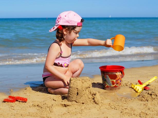 Bambina gioca sulla spiaggia con secchio e paletta.