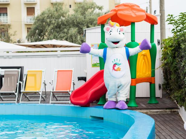 Mascotte colorata vicino a una piscina con scivolo.