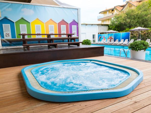 Piscina con idromassaggio e cabanas colorate.