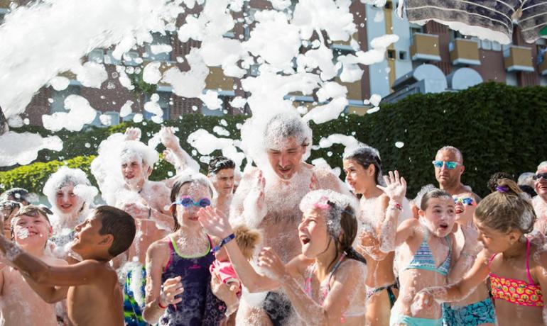 Persone si divertono in una festa di schiuma all'aperto.