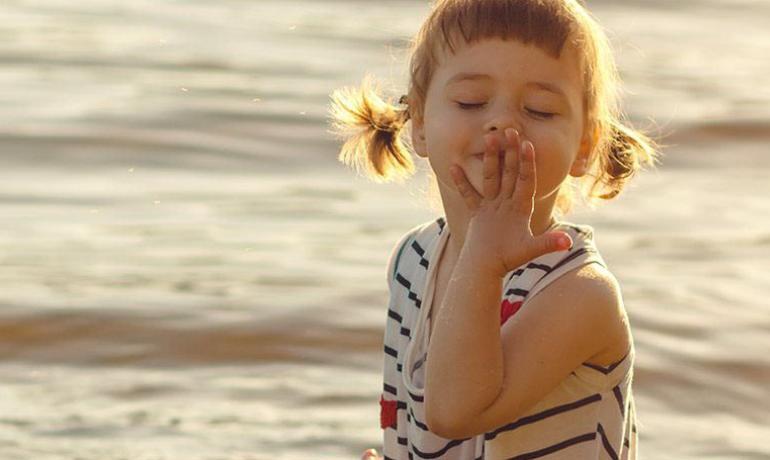 Bambina felice al mare, baciando il sole.