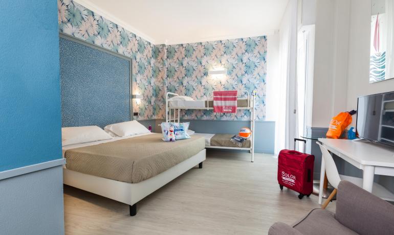 Chambre lumineuse et colorée avec lit double et lits superposés.