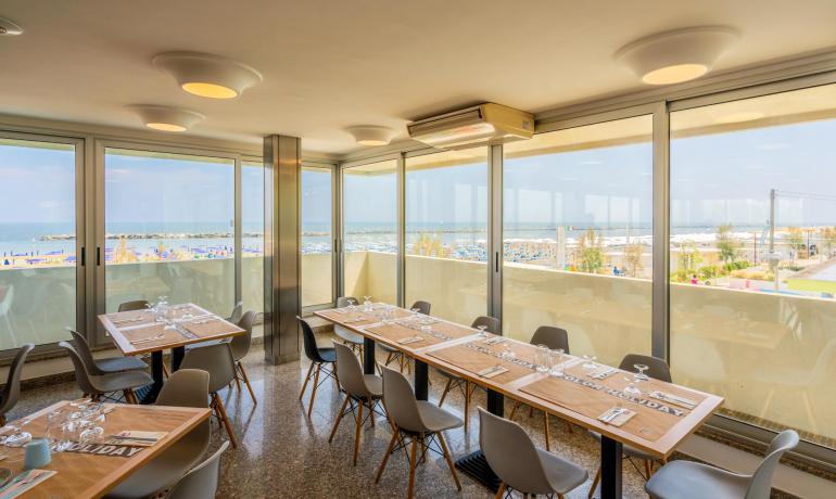 Restaurant lumineux avec vue sur la mer et mobilier moderne.