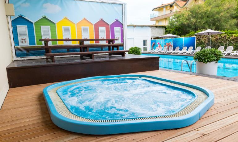 Piscine avec jacuzzi, plantes et fond coloré.