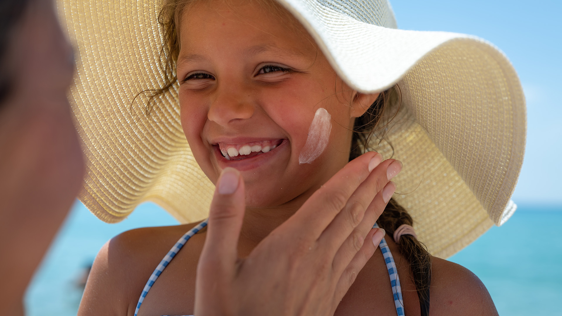 Famiglia cammina sulla spiaggia, tra ombrelloni e sdraio, verso il mare.