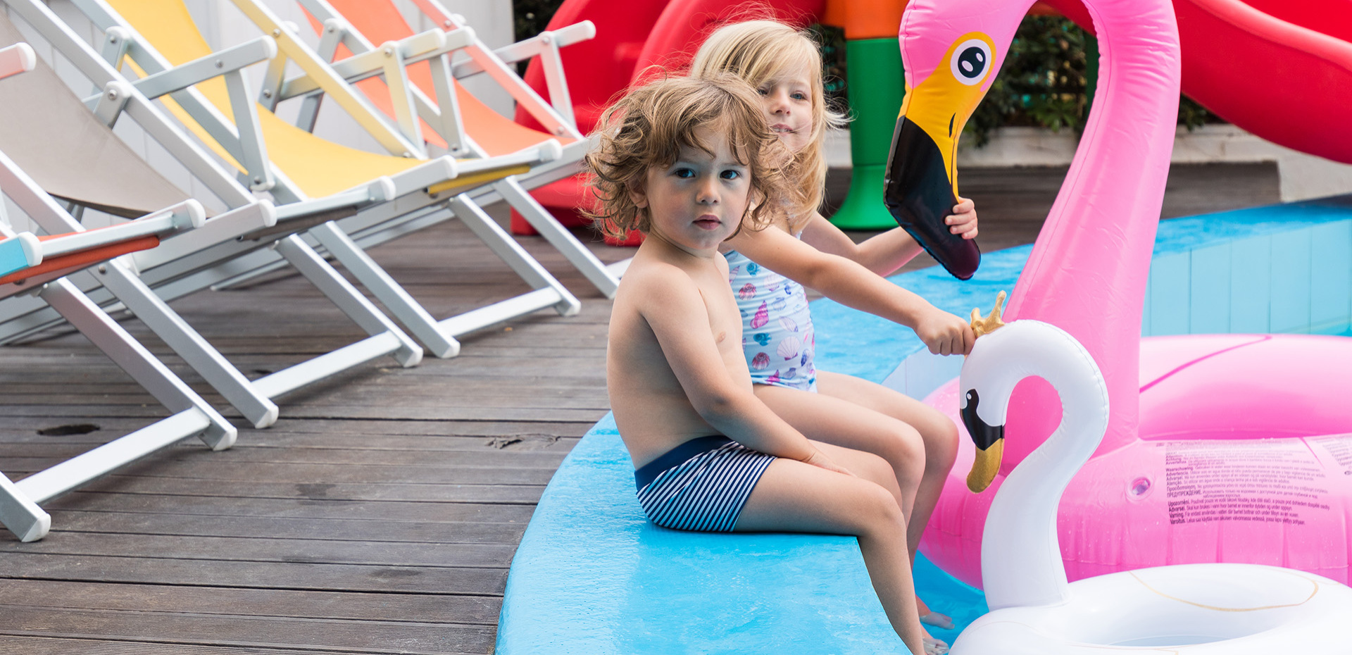 Piscina con giochi acquatici e gonfiabili colorati in un ambiente soleggiato.