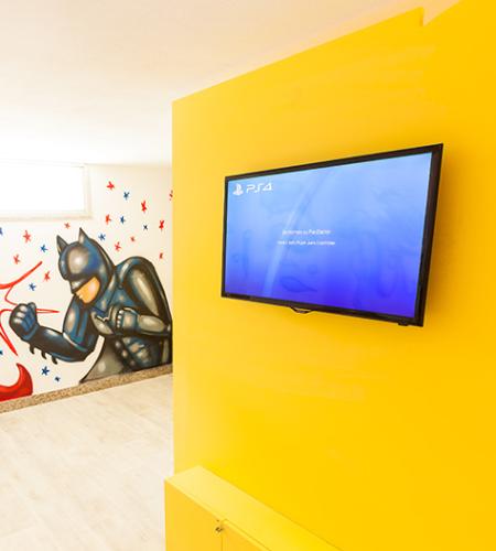 Sala giochi con supereroi, TV e arredi colorati per bambini.