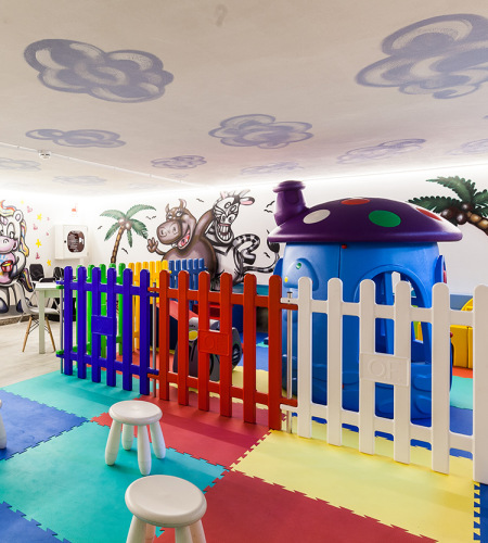 Bambina e donna giocano insieme su un tappeto colorato con giocattoli educativi.