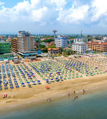 Crowded beach, colorful umbrellas, calm sea, lively summer, bustling city in the background.