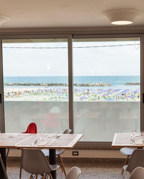 Vista mare da ristorante, sedie moderne, atmosfera rilassante.