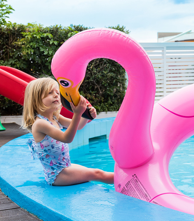 Bambino in piscina con braccioli arancioni, seduto vicino all'acqua.