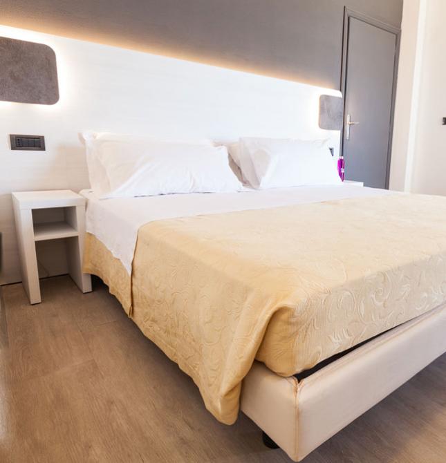 Camera moderna, letto accogliente, atmosfera luminosa e valigia rossa.