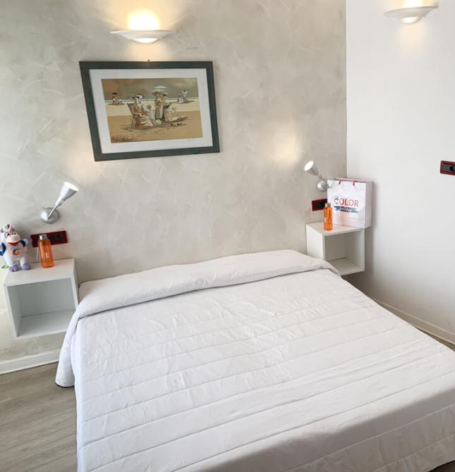 Camera luminosa con letto bianco, arredamento semplice e accogliente.