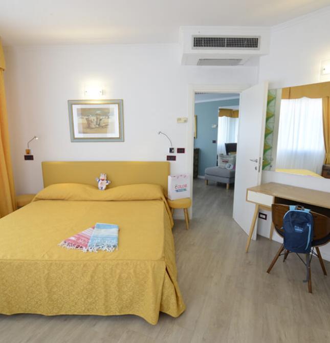 Camera luminosa, accogliente, con letto giallo e arredi moderni.