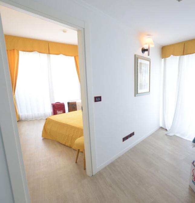 Luminosa stanza moderna con poltrona accogliente, tende gialle e dettagli eleganti.