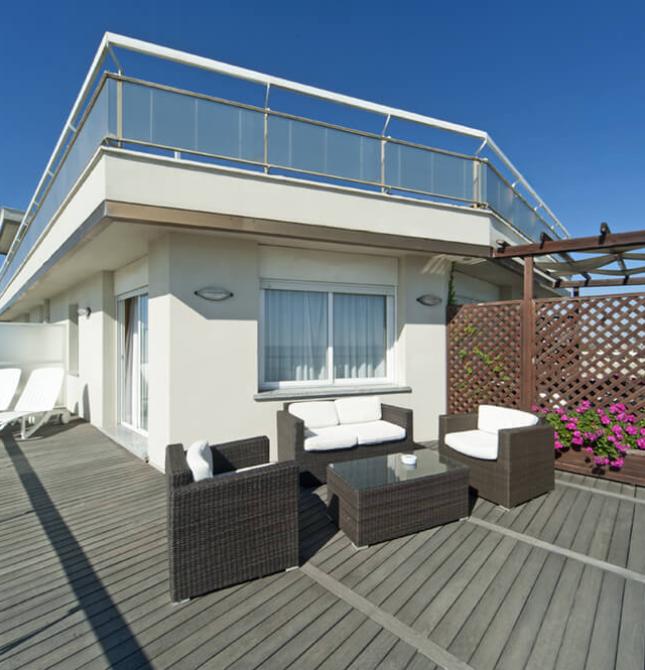 Terrazza moderna con mobili eleganti, sole splendente e fiori colorati.
