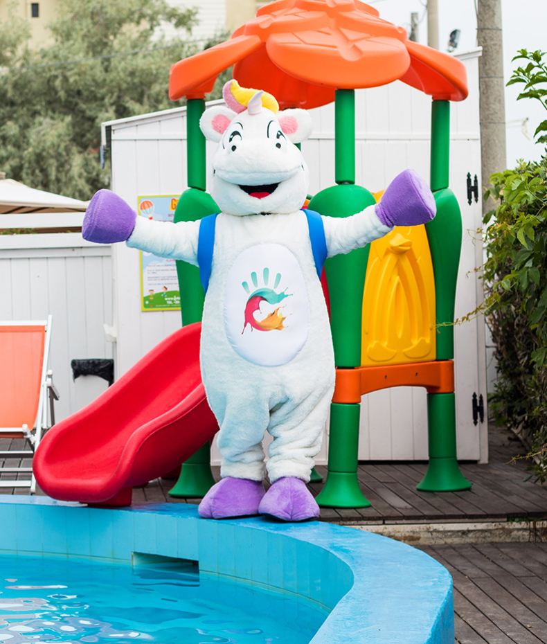 Un unicorno mascotte gioioso vicino a uno scivolo e una piscina.
