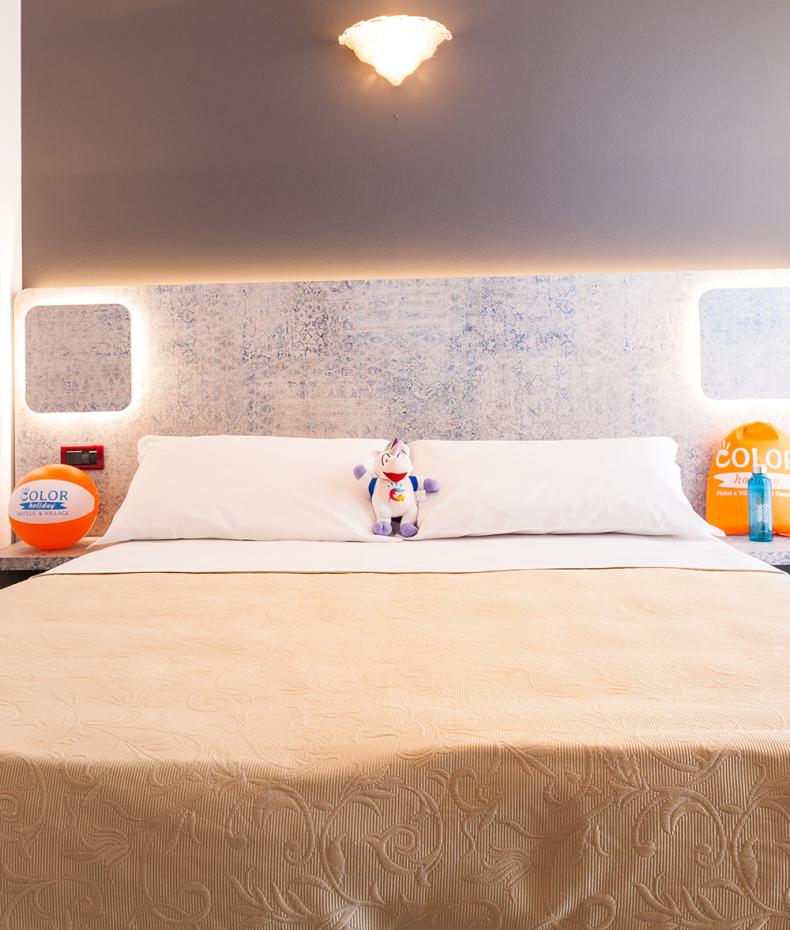 Bambina salta sul letto, mentre una donna incinta la osserva sorridendo.