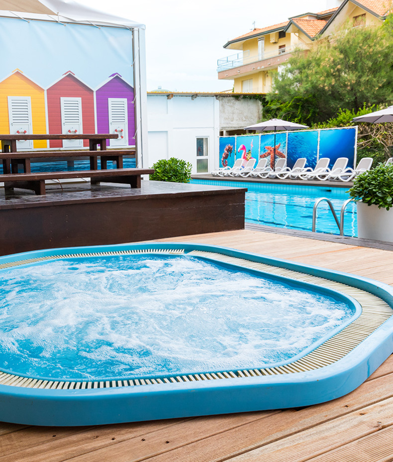 Piscina per bambini con giochi d'acqua e gonfiabile colorato in cortile soleggiato.
